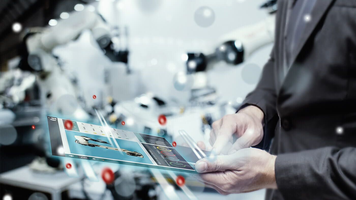 Mann mit futuristischem Tablet in einer Fabrik mit End-to-End Digitalisierung