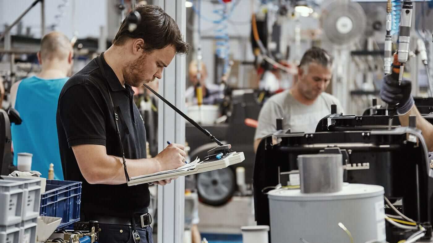 Mann mit Klemmbrett in einer Fabrik kontrolliert die Fertigung