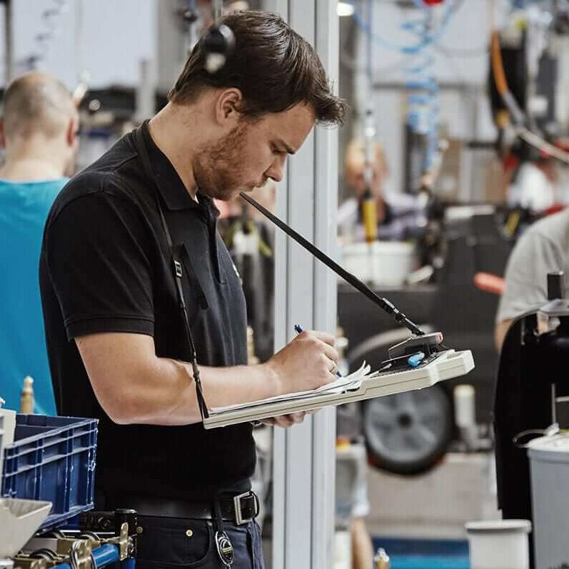 Lean Training Mann mit Klemmbrett in einer Fabrik kontrolliert die Fertigung