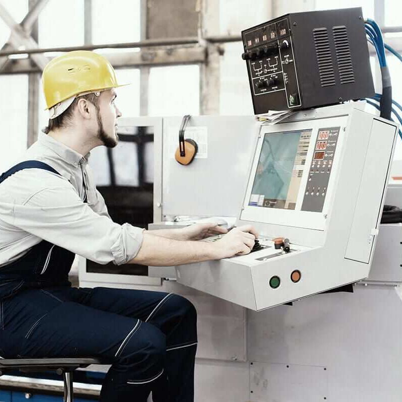 Mann sitz an einer Produktionsmaschine