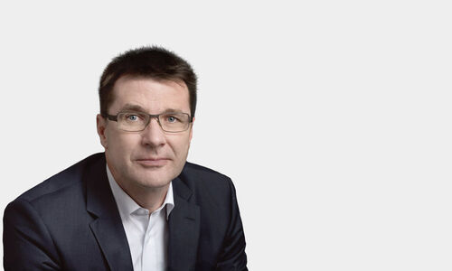 Portraitfoto von Elmar Hubner vor grauem Hintergrund