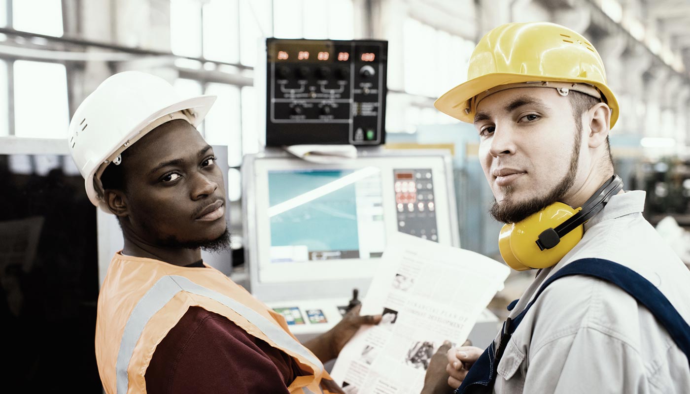 Arbeiter in einer Fabrikhalle blicken in die Kamera